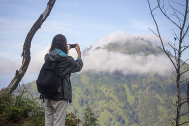 Indonesien, Java, Frau wandert in den Bergen und macht Fotos mit Smartphone - KNTF000394