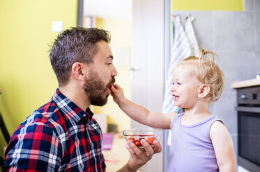 Vater und Tochter essen Tomaten in der Küche - HAPF000500