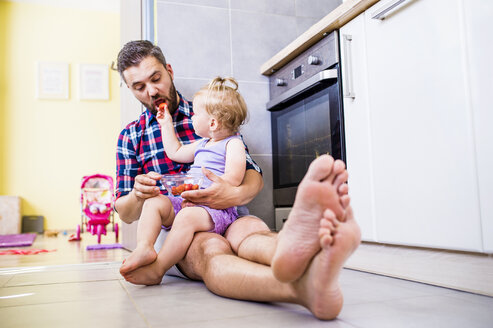 Father and daughter eating tomatoes in kitchen - HAPF000503