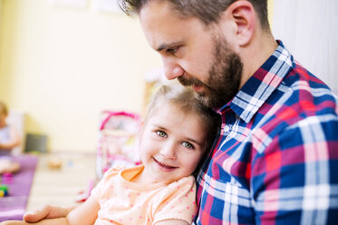 Little girl sitting on father's lap, smiling - HAPF000511