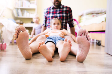 Vater und Tochter zu Hause, die ihre nackten Füße zeigen - HAPF000515