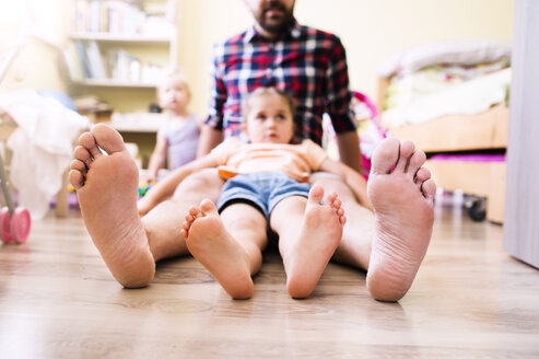 Father and daughter at home, showing their bare feet - HAPF000515