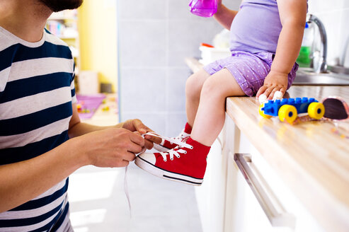 Father putting his daughter shoes on - HAPF000519