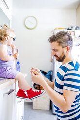 Vater zieht seiner Tochter die Schuhe an - HAPF000521