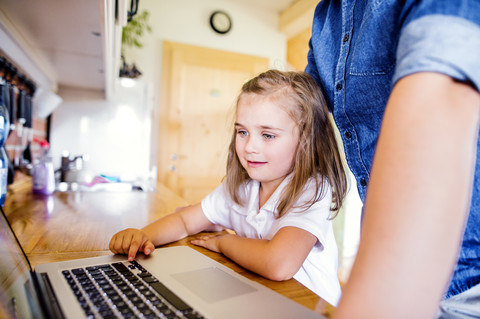 Vater und Tochter benutzen Laptop zu Hause, lizenzfreies Stockfoto