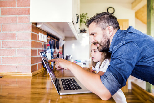Vater und Tochter benutzen Laptop zu Hause - HAPF000532