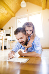 Father and daughter lying on floor, drawing on digital tablet - HAPF000536