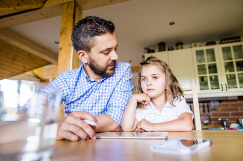 Vater und Tochter sitzen zu Hause und benutzen ein digitales Tablet, lizenzfreies Stockfoto