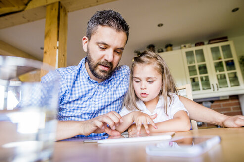 Vater und Tochter sitzen zu Hause und benutzen ein digitales Tablet - HAPF000540