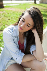 Junge Frau im Park sitzend mit geschlossenen Augen - VABF000626