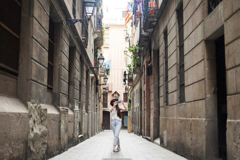 Junger Tourist auf Entdeckungstour durch die Straßen von Barcelona, mit Handy - VABF000634