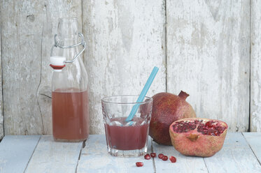 Glass and bottle of pomegranate juice and whole and sliced pomegranate - ASF005916