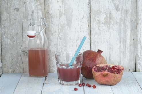 Glas und Flasche mit Granatapfelsaft und ganzen und geschnittenen Granatäpfeln - ASF005916