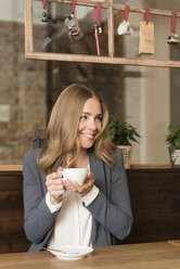 Portrait of happy young woman drinking coffee in a coffee shop - KAF000157
