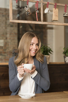 Porträt einer glücklichen jungen Frau beim Kaffeetrinken in einem Café - KAF000157