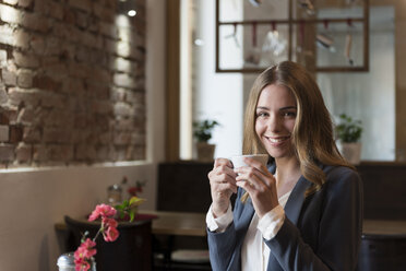 Porträt einer lächelnden jungen Frau beim Kaffeetrinken in einem Café - KAF000163