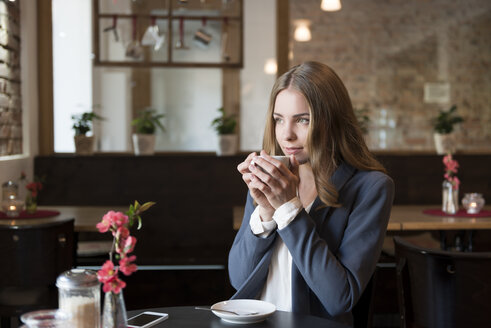 Portrait of young woman drinking coffee in a coffee shop - KAF000164