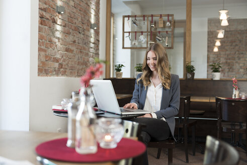 Young woman using laptop in a coffee shop - KAF000167