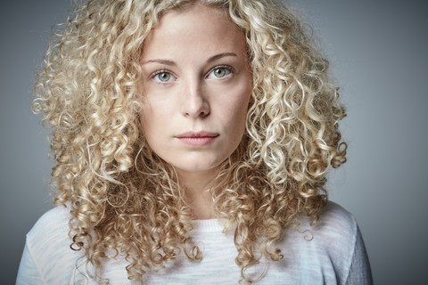 Porträt einer ernsten blonden Frau mit lockigem Haar, lizenzfreies Stockfoto