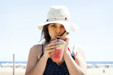 Junge Frau trinkt einen Cocktail am Strand - VABF000641