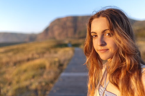 Porträt einer jungen Frau bei Sonnenuntergang am Strand - MGOF002001
