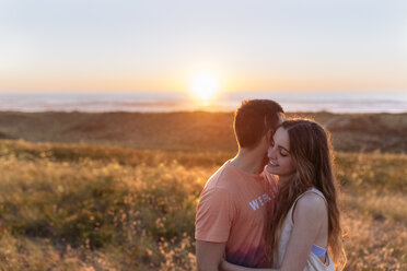 Romantic young couple embracing on the beach at sunset - MGOF002007