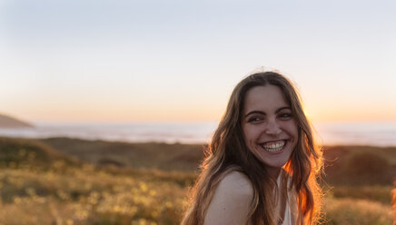 Porträt einer jungen Frau bei Sonnenuntergang am Strand - MGOF002009