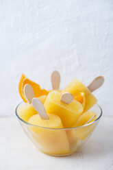 Glass bowl of homemade orange popsicles - MYF001627