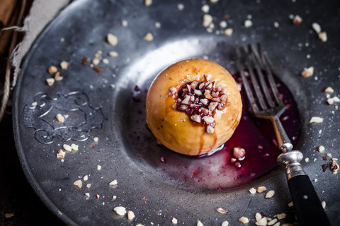 Bratapfel mit Nuss- und roter Marmeladenfüllung auf Blechteller, lizenzfreies Stockfoto