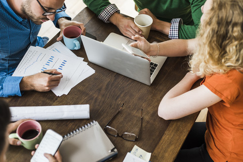 Colleagues at table with cell phones, laptop and document stock photo