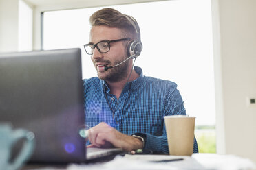 Man with headset and laptop in office - UUF007878