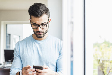 Junger Mann schaut auf sein Handy - UUF007916