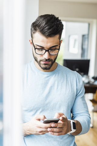 Junger Mann mit Blick auf sein Handy, lizenzfreies Stockfoto