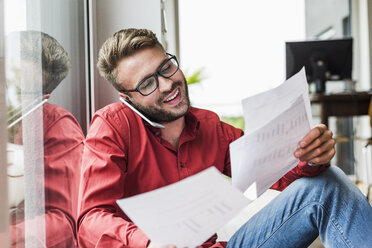 Young man with documents talking on the phone - UUF007922