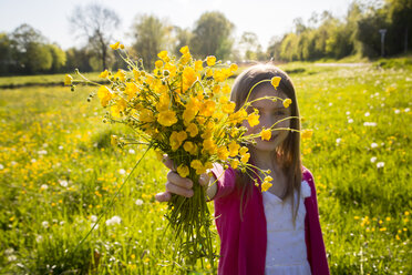 Girl on a meadow gifting bunch of buttercups to viewer - SARF002800