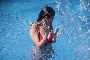 Woman standing in a pool being splashed with water - ABZF000748