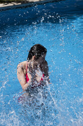 Frau, die in einem Pool steht und mit Wasser bespritzt wird - ABZF000749
