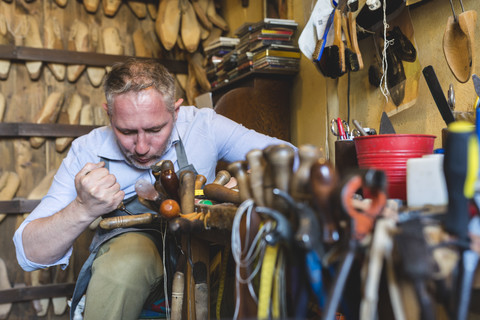 Schuster bei der Herstellung von Schuhen in seiner Werkstatt, lizenzfreies Stockfoto