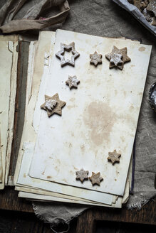 Selbstgebackene Weihnachtsplätzchen mit Puderzucker auf altem Buch - SBDF002972