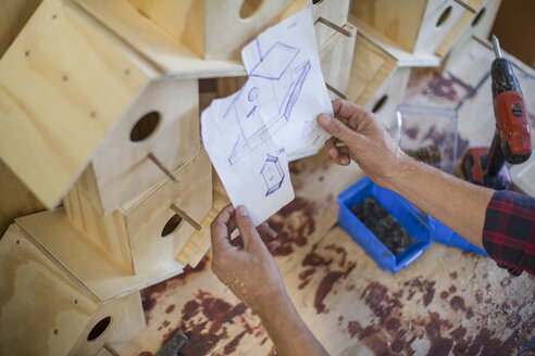 Mann beim Zusammenbau von Vogelhäusern in einer Werkstatt mit Plan - ZEF008803