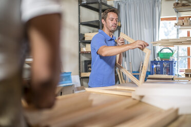 Mann betrachtet den Holzrahmen für die Vorbereitung der Leinwand in der Werkstatt - ZEF008812