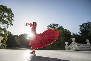 Rot gekleidete Frau tanzt Flamenco auf Terrasse bei Gegenlicht - ABZF000766