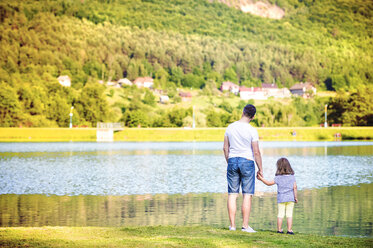 Rückenansicht eines Vaters und seiner kleinen Tochter am Ufer des Wassers - HAPF000555