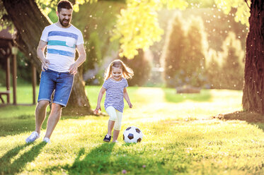 Glückliches kleines Mädchen, das mit seinem Vater in einem Park Fußball spielt - HAPF000572