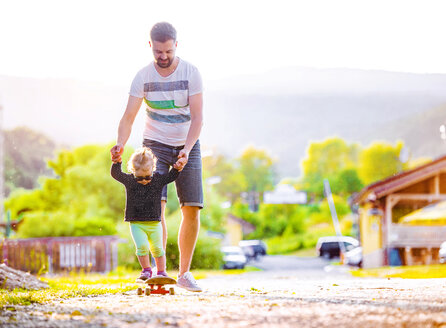 Father and his little daughter having fun with skateboard - HAPF000583