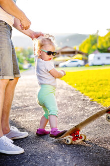 Porträt eines kleinen Mädchens mit Sonnenbrille, das auf ein Skateboard tritt - HAPF000584