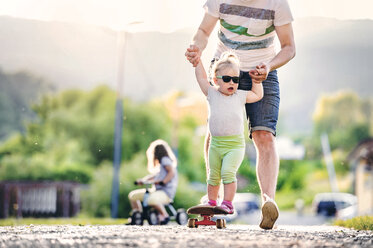 Father and his little daughter having fun with skateboard - HAPF000585