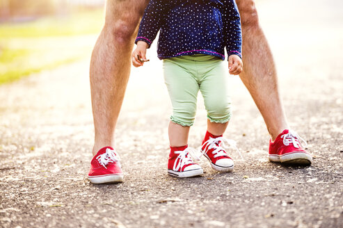 Beine eines kleinen Mädchens und ihr Vater tragen beide rote Turnschuhe - HAPF000587