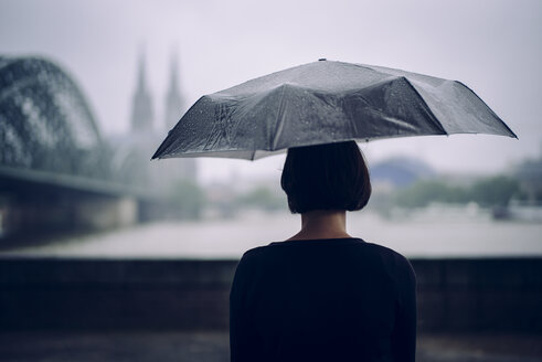 Germany, Cologne, back view of woman with umbrella on a rainy day - DASF000044