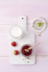 Erdbeermarmelade und Milchglas auf Schneidebrett - MYF001668